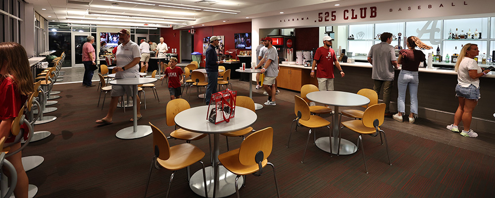 People milling about the .525 Club which has a bar and round tables for seating