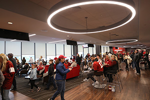 People milling about buffets and seating groups with a large round light overhead