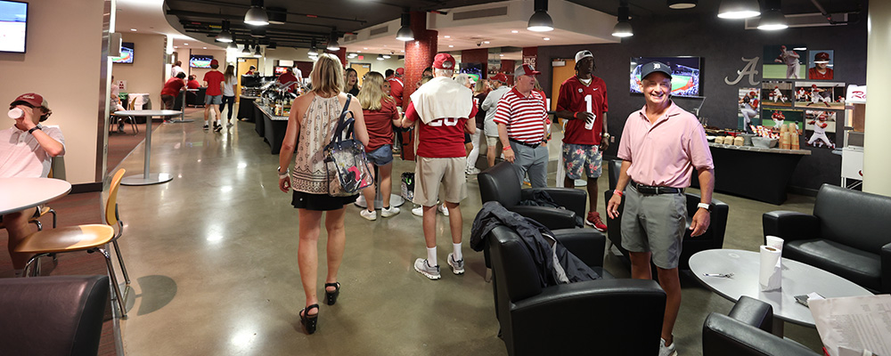 People walking around the Home Plate Club with the buffet in the background