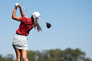 Kynadie Adams with the club behind her head after hitting the ball